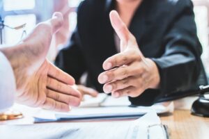 settlement between private and government officials Close-up of lawyers shaking hands in an office, offering counsel and advice to facilitate a fair settlement between private and government officials, with an Instagram-style filter.