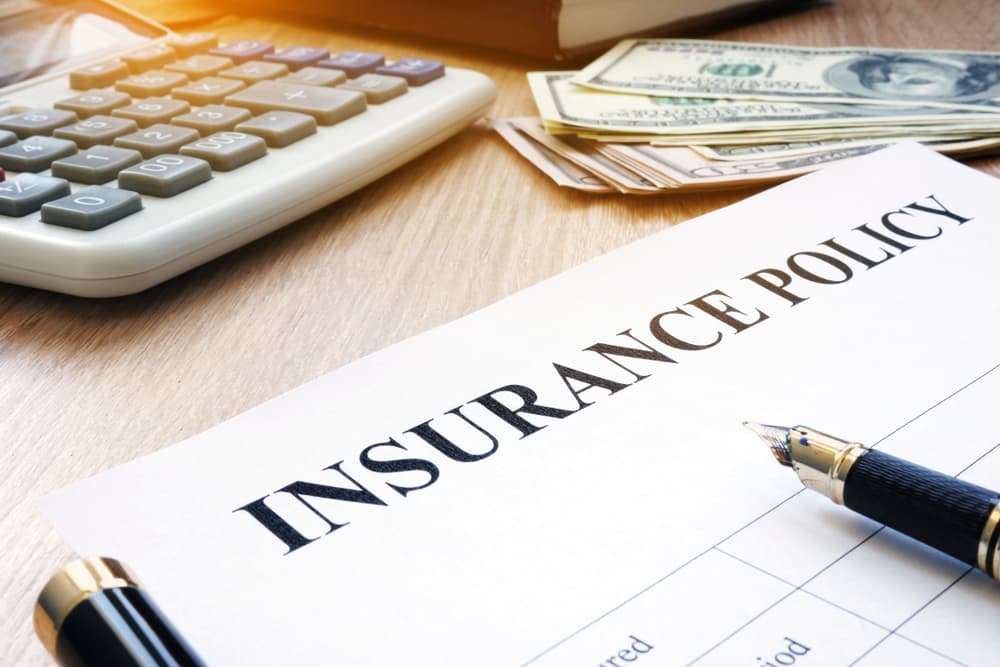 Insurance policy and dollar bills on an office desk.