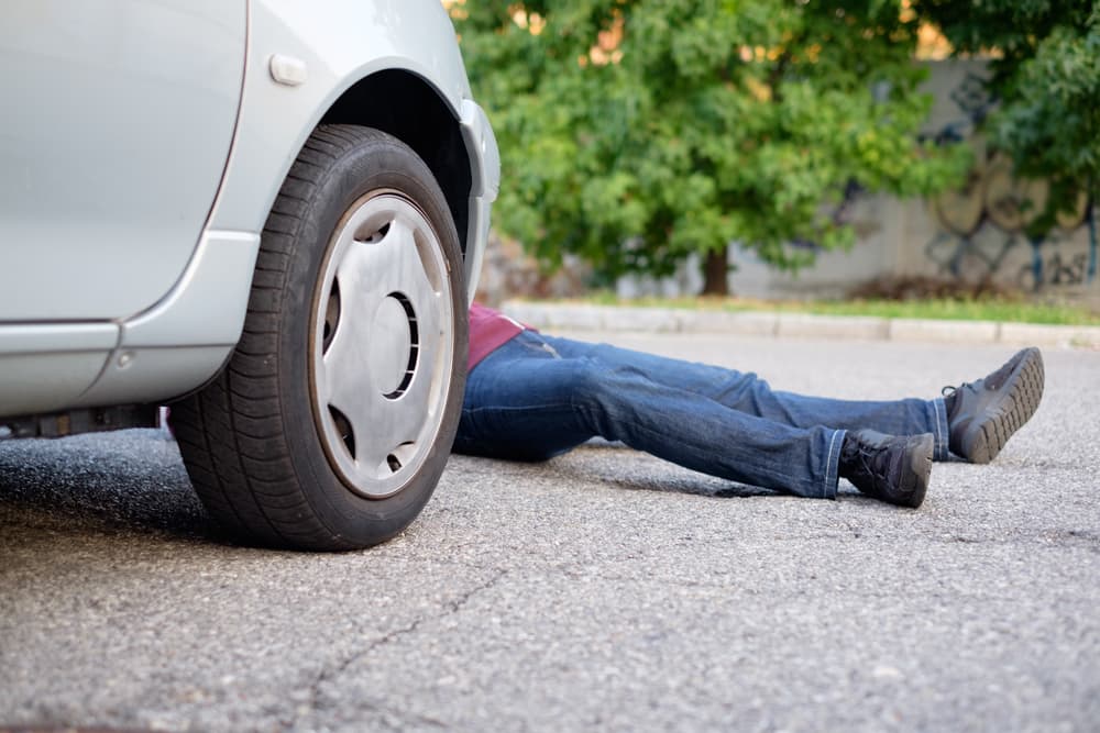 The pedestrian was injured on the road after being struck by a car.