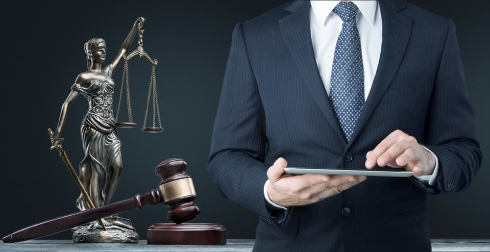 An attorney's table with legal documents, a gavel, and a balance scale in the background, all set against a black backdrop, symbolizing authority and professionalism in law.