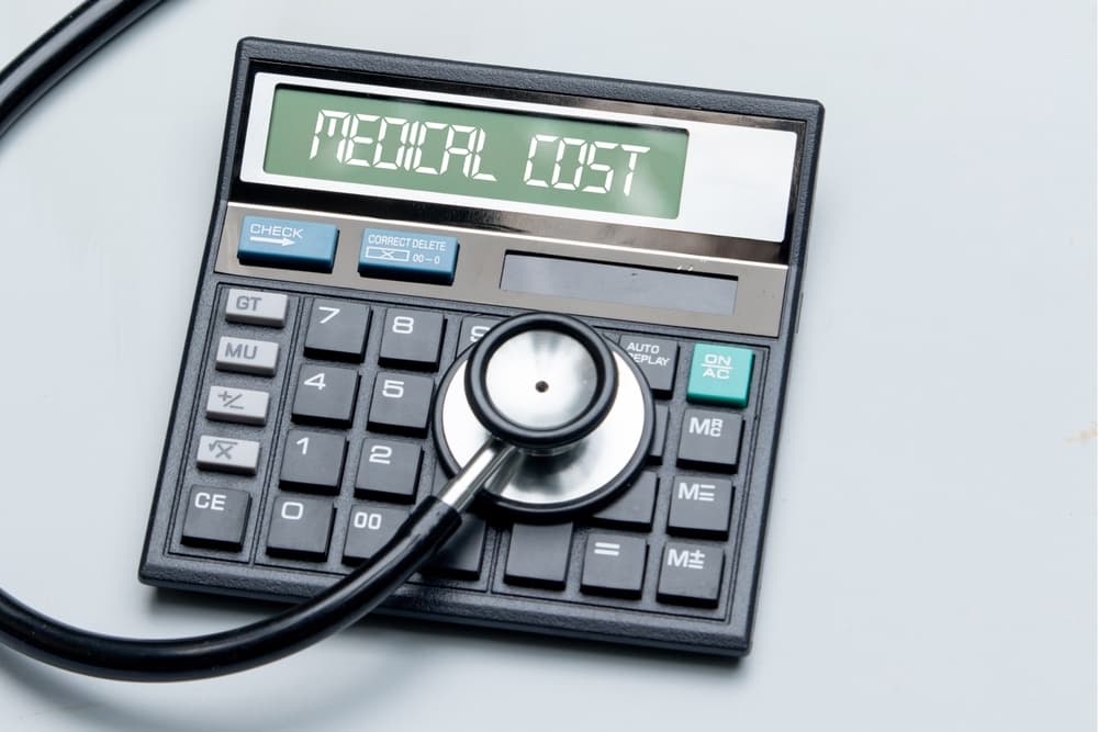Medical cost concept with a calculator and stethoscope placed on a table.