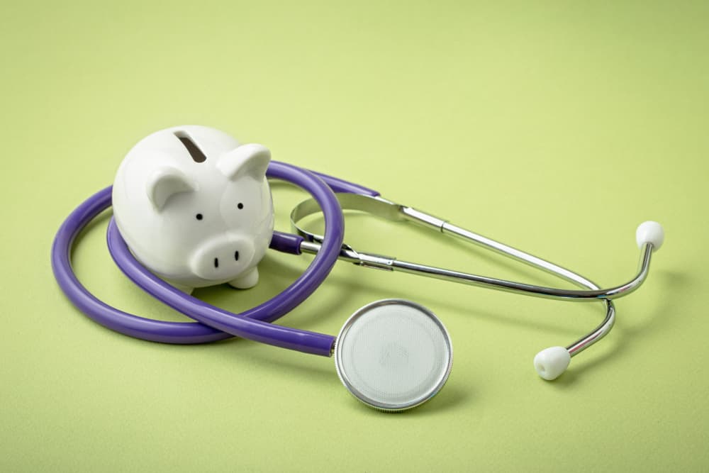 Piggy bank with stethoscope on light green background. Financial recovery or medical insurance expenses.