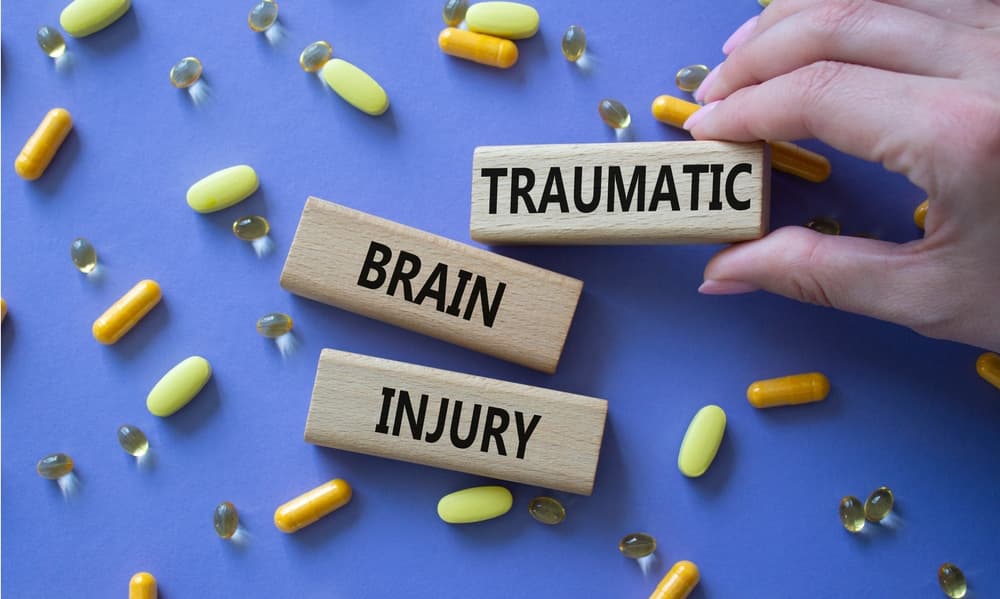 Traumatic Brain Injury symbol. Concept words Traumatic Brain Injury on wooden blocks. Beautiful purple background with pills. Doctor hand. Healthcare and Traumatic Brain Injury concept.