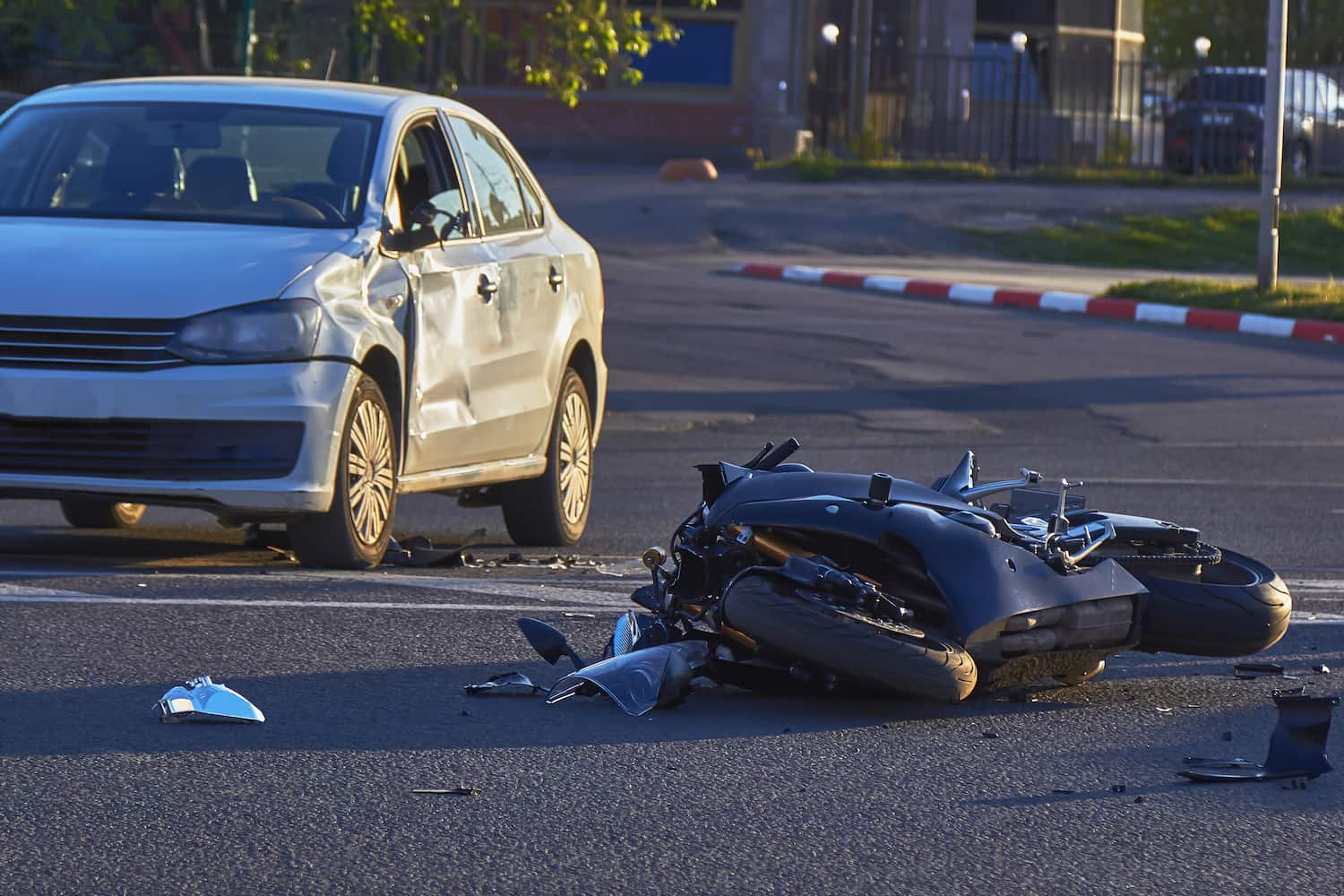 Left-turn motorcycle accident scene on Long Island with damaged car and fallen bike at intersection