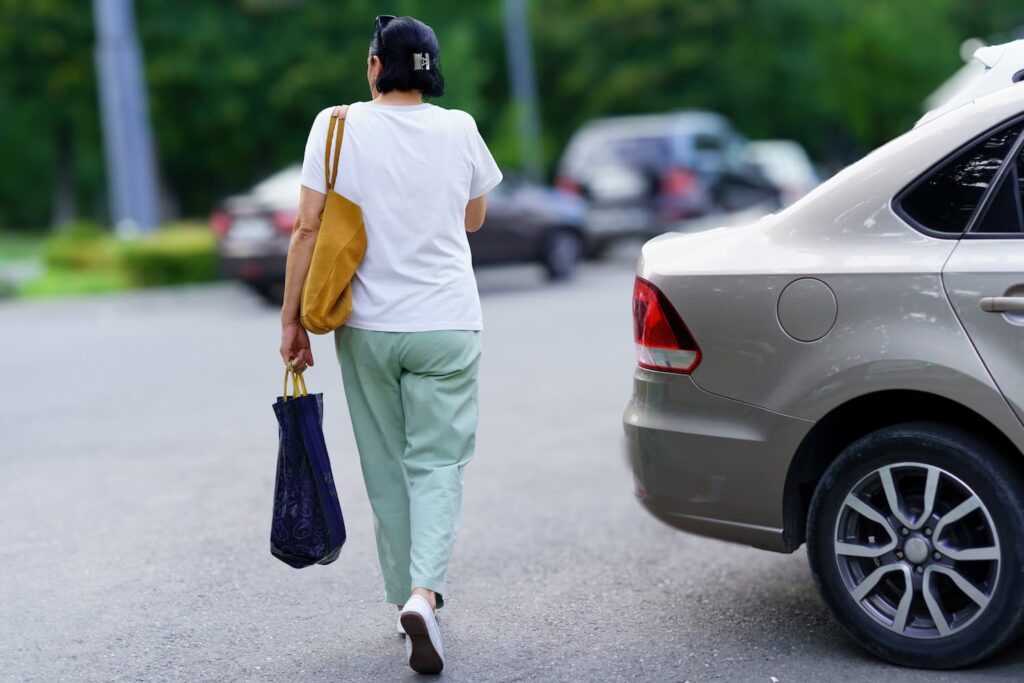 Pedestrian Hit-and-Run Risk in Parking Lots and Driver Liability Pedestrian walking in a parking lot near a reversing car illustrating hit-and-run risk and driver negligence in shared spaces